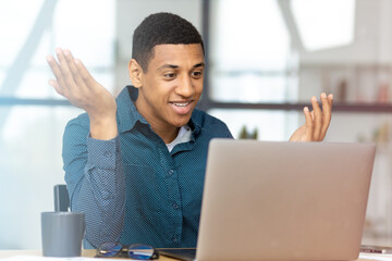 Man working using laptop. Young Afro American businessman, talking with colleagues or partners on video call sitting in a modern office, discussing something