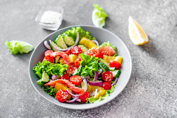 Fototapeta na wymiar Salted salmon salad with fresh green lettuce, cucumbers, tomatoes, sweet peppers and red onions on a stone background. Ketogenic, keto or paleo diet lunch bowl.