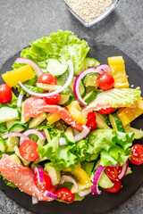 Salted salmon salad with fresh green lettuce, cucumbers, tomatoes, sweet peppers and red onions on a stone background 