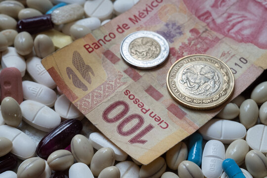 Photo of a 100 Mexican peso bill and two coins among pills of many shapes and colors that could probably be used to illustrate the economics of the pharmaceutical industry  in Mexico.