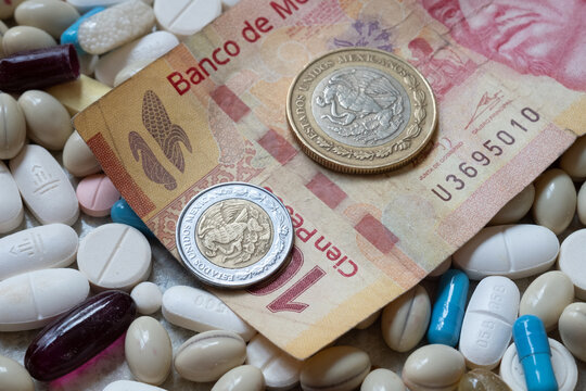 Photo of a 100 Mexican peso bill and two coins among pills of many shapes and colors that could probably be used to illustrate the economics of the pharmaceutical industry  in Mexico.