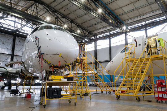 Ukraine, Kyiv - November 25, 2020: The Embraer E190LR UR-EMD aircraft is in the hangar for technical repair and maintenance. Aircraft diagnostics, storage, service. Plane. Ladders for mechanics
