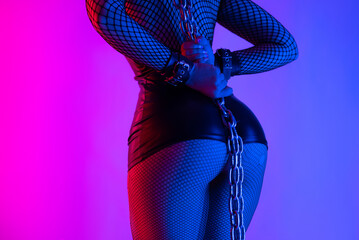 sexy buttocks close-up of a girl in a latex bdsm mistress costume with torn tights in neon light