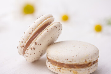 Obraz na płótnie Canvas White creamy macarons on white floral background. Sweet cookies. Traditional French dessert for coffee. High quality photo