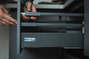 Furniture maker assembling new modern drawer system with adjustment mechanism - obrazy, fototapety, plakaty