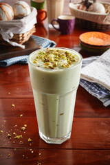 A glass of healthy fresh avocado milkshake isolated on wooden background side view
