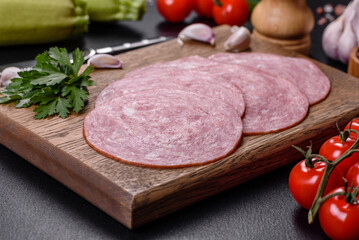 Slices of delicious fresh sausage on a wooden cutting board © chernikovatv