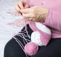 Process of yarn knitting by elderey woman: arms, spins, thread close-up