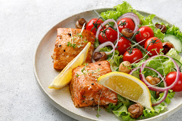 Salmon fillet with green fresh vegetable salad, tomatoes cherry, onion on ceramic plate. Concept keto diet healthy food. Dinner idea. © Maria