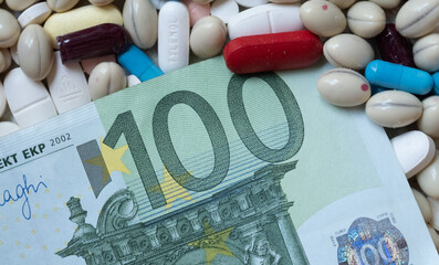 Photo of a 100 euro bill among pills of many shapes and colors that could probably be used to illustrate the economics of the pharmaceutical industry or drug trafficking in Europe.