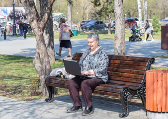 Plakat energetic senior woman freelancer working remotely using electronic portable computer on bench