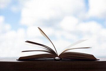 an open book lies on the table against the blue sky