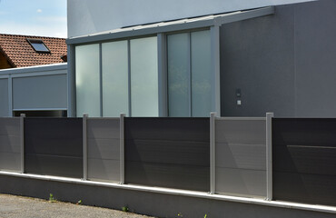 Sichtschutzwand aus Metall mit Tor im Eingangsbereich als Grundstücksabgrenzung vor einem Wohnhaus