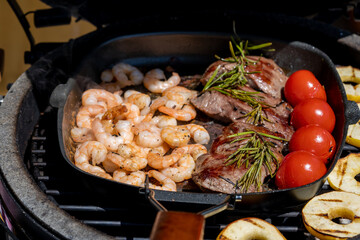 grilled shrimps, venison meat, cherry tomatoes and apple rings  from a bbq grill at a sunny summer day on the balcony