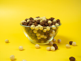 breakfast cereal, Vanilla and chocolate corn balls in a glass bowl on a yellow background