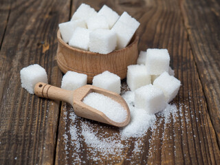 Fototapeta na wymiar Stack of sugar cubes and granulated sugar in a wooden scoop
