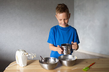 The child prepares dough in metal bowls and looks away . Pour flour