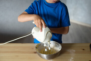 A child prepares dough in metal bowls. Lower the mixer into the bowl