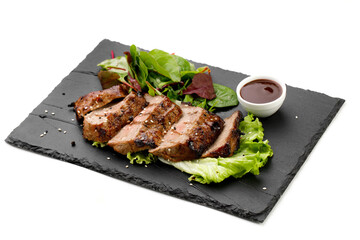 Grilled beef nicely cut with sauce arranged on black plate with white background