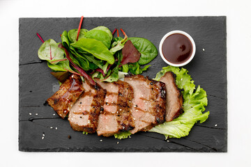 Grilled beef nicely cut with sauce arranged on black plate with white background