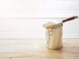brush in white paint on open can on wooden floor or floor repair and painting concept