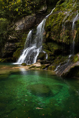Naklejka na ściany i meble Alpine Waterfall and Emerald green lagoon on Water Stream Gljun in Bovec Slovenia