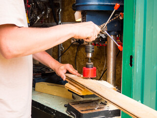 man working on vertical drilling machine in his workshop