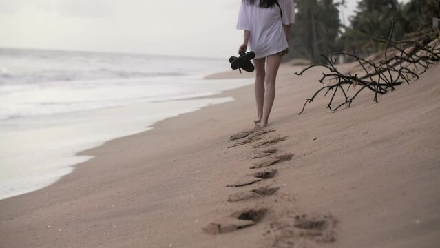 a girl walks on the beach barefoot