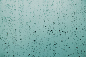 Blue raindrops on glass, abstract liquid texture.