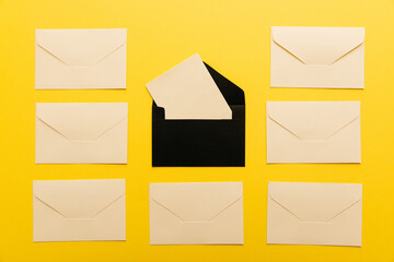 Light envelopes with card inside isolated on yellow background. Top view