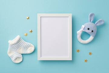 Baby accessories concept. Top view photo of photo frame tiny socks knitted bunny rattle toy and...