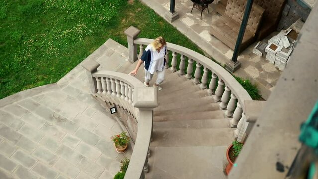 young woman wearing white t-shirt walking up the stairs. Slavic girl vacation. Outdoors. Summertime. Old castle stairs. High quality 4k footage