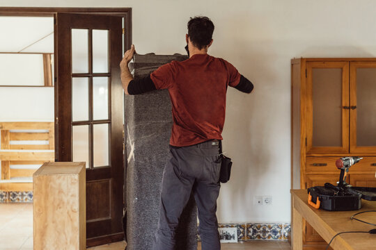 Moving Worker Packing A Piece Of Furniture With A Blanket