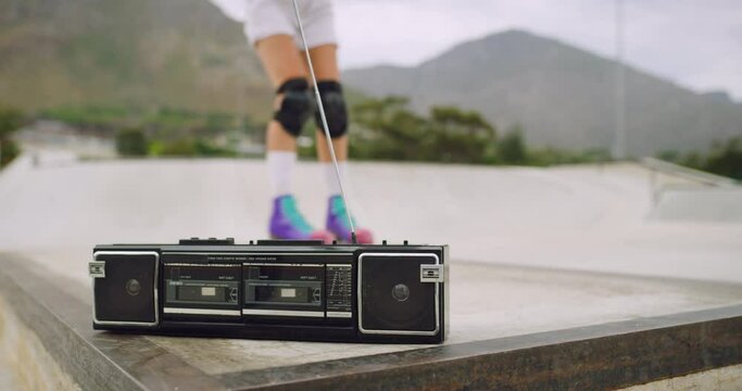 Closeup of a retro radio panning to cool urban skaters practicing their skills. Young fun female rollerbladers playing a cassette player in a skate park outside. Girls listening to music on a boombox