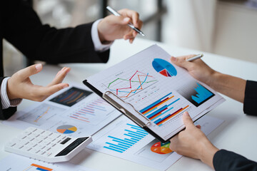 Close up of hands are working on paperworks that shows graft and chart of accounting and financial on table in office space.