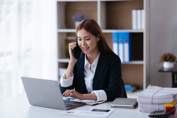 Young business woman discussing and talking with co-worker and client via smartphone and laptop with happy face.