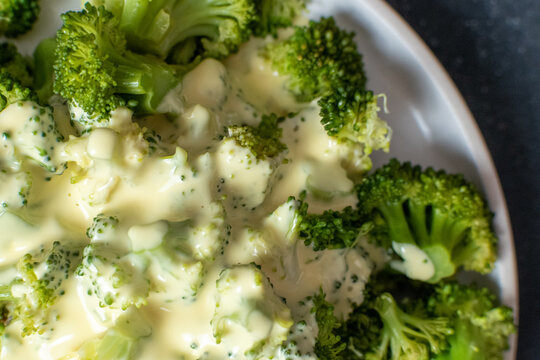 vegetarian food of steamed broccoli florets served with hollandaise sauce
