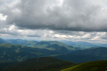 Fototapeta premium Low cloudy sky over the mountain peaks covered with dense forest. Carpathian mountains, Ukraine. Travel background.
