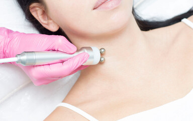 A young woman is lying on the RF-lifting procedure for face skin tightening and face contour correction. Close-up.