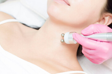 A young woman is lying on the RF-lifting procedure for face skin tightening and face contour correction. Close-up.