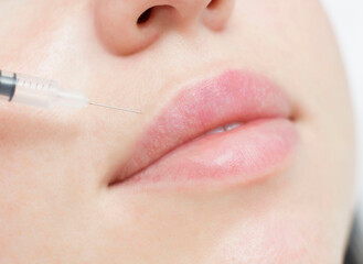 Woman having procedure lip augmentation. Syringe near womans mouth, injections for increase lips shape