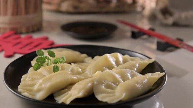 Dim sum. Homemade Chinese dumplings are served on a black plate. They eat with chopsticks. Oriental cuisine, light snacks for a traditional lunch. High quality 4k footage