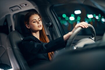 Fototapeta na wymiar horizontal photo of a nice woman in a black shirt driving a car while driving at night