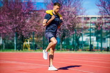 Fototapeta premium Muscular young man exercising with heavy weight bag in the sport stadium. Sporty man working out with heavy weight bag.