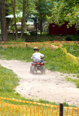 Boy drive four-wheller ATV quad bike. back view. a boy rides on a training fenced track for children's competitions . High quality photo