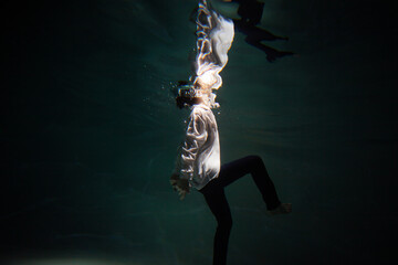 Beautiful underwater shooting, guy in white shirt and pants has fallen under the water and is...