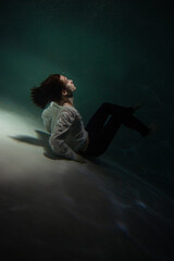 Beautiful underwater shooting, guy in white shirt and pants has fallen under the water and is...