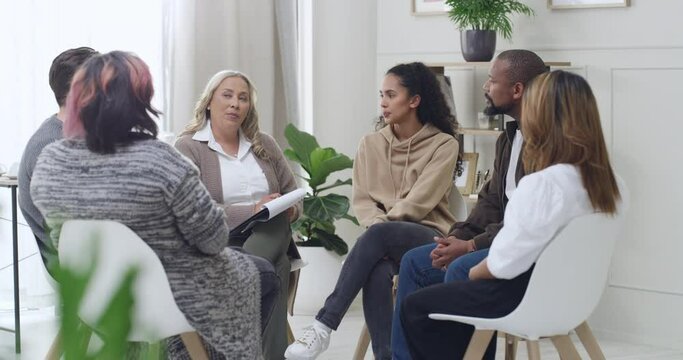 diverse support group during a meeting with a professional mature female therapist. Group of employees looking serious during a team counselling session. Mental health in the professional workplace