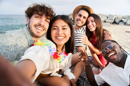 Sunset beach - Group of five cheerful young friends taking selfie portrait. Happy people looking at the camera smiling. Concept of community, youth lifestyle and friendship