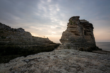 rock formations at seaside and colorful sunset with clouds